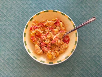A photo of a bowl of pasta with tomatoes and feta