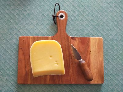 A photo of unwrapped very old edam on a cheese board. It is a rich yellow colour with a couple of dimples.