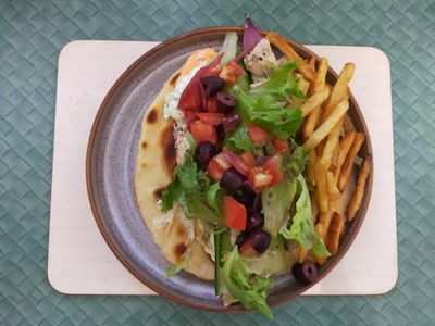 A photo of a souvlaki wrap with some shoestring fries on the side