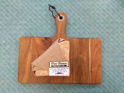 A photo of wrapped double cream brie on a chopping board
