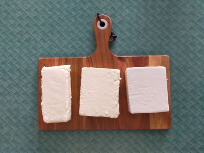 Photo of three unwrapped blocks of feta on a chopping board