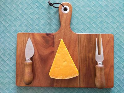 A photo of unwrapped red leicester on a cheese board. It is very orange, much more than a regular cheese.