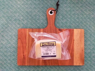 A photo of pecorino still in its wrapping on a cheese board