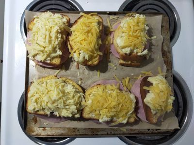Photo of six croque monsieurs laid out on an oven tray, ready to be toasted