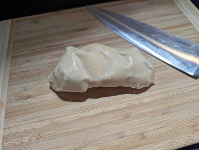 Photo of raw, uncut scamorza in a lump on a chopping board